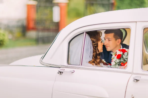 Feliz casal recém-casado beijando em um banco de trás do carro vintage — Fotografia de Stock