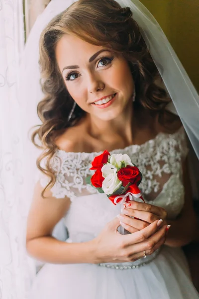 Close-up portrait of beautiful bride in wedding dress holding a cute bouquet with red and white roses — Stock Photo, Image