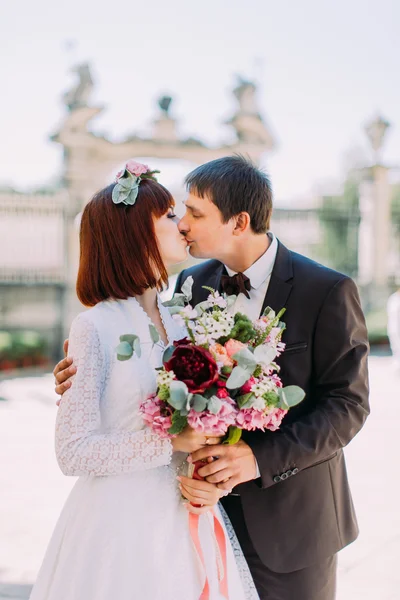 Mariage de luxe couple marié, mariée et marié baisers dans la vieille ville avec bouquet — Photo