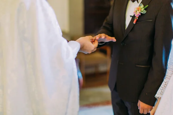 The priest dresses a ring on finger to groom during church wedding — Stock Photo, Image
