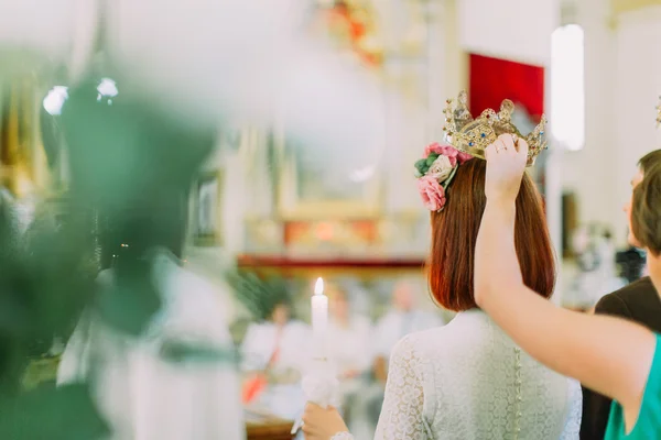 Nevěsta držící svíčku a družička nad ní drží svatební korunku, pohled zezadu — Stock fotografie