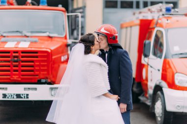 Mutlu evlilik çift iki kırmızı itfaiye araçları arasında öpüşme