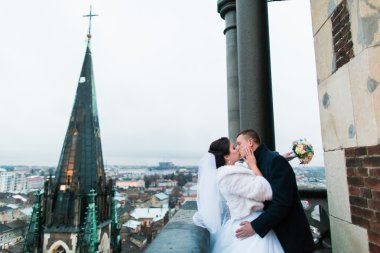 Mutlu yeni evli gelin ve damadın eski Gotik Katedrali balkonda tatlı bir öpücük var