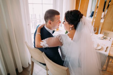 Restoranda kucaklayan mutlu yeni evliler. Arkadan görünüm