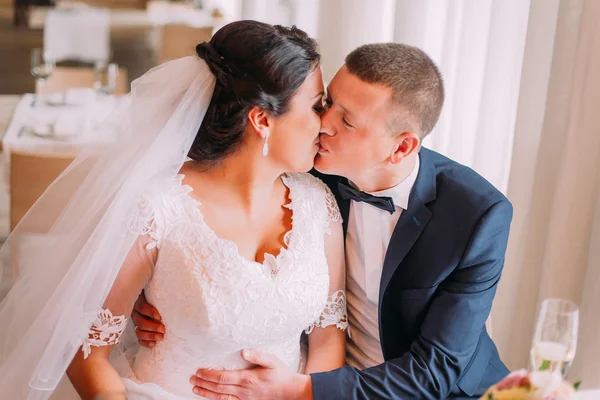 Szczęśliwy newlywed para namiętnie całuje się na stole w restauracji — Zdjęcie stockowe