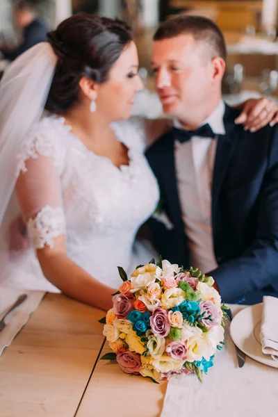 Felices recién casados abrazando y soñando con su nueva vida matrimonial en la sala de restaurantes en la mesa —  Fotos de Stock