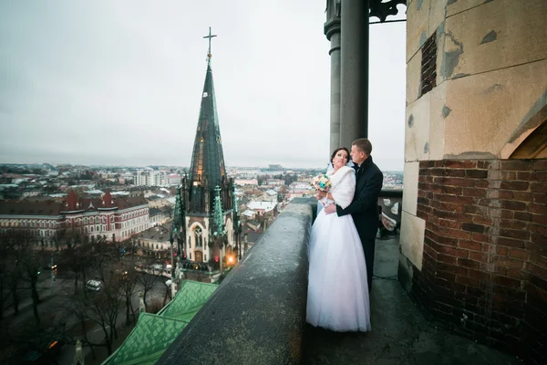 Noiva e noivo recém-casados felizes segurando um ao outro na varanda da velha catedral gótica — Fotografia de Stock