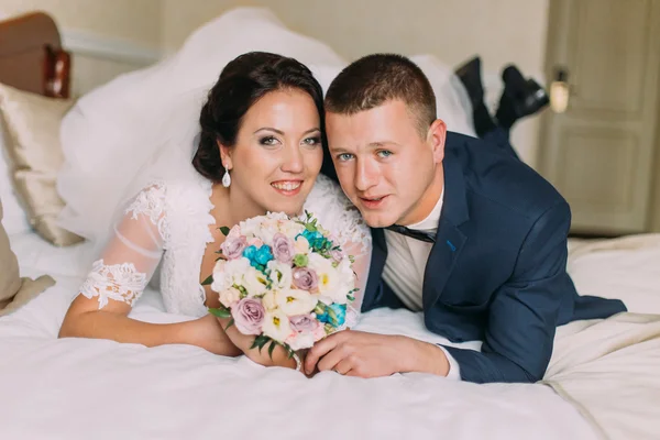 Ευτυχισμένη νύφη και τον γαμπρό θέσει σε κρεβάτι σε δωμάτιο ξενοδοχείου αφού γαμήλιες τελετές. Νεόνυμφους στο μήνα του μέλιτος — Φωτογραφία Αρχείου