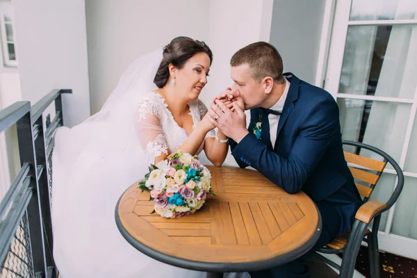 Gorgeous bride and elegant groom sit at the table on balcony. Enloved newlyweds honeymoon concept — Stock Photo, Image