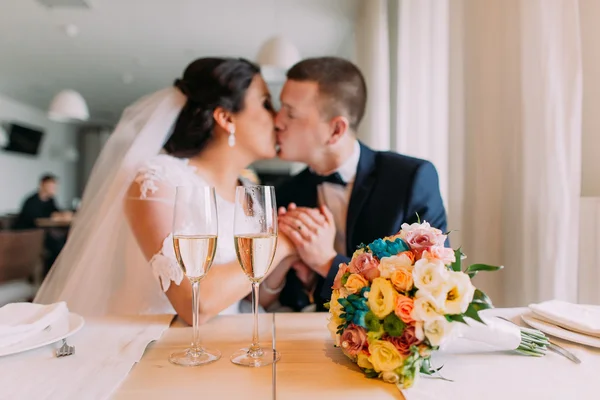 Gelukkig jonggehuwden delen een kus champagne drinken in restaurant, vieren het begin van het huwelijksleven — Stockfoto
