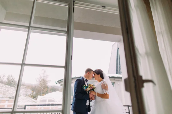 Splendida sposa ed elegante sposo in posa sul balcone. Concetto di luna di miele per sposi novelli. Colpo basso angolo — Foto Stock