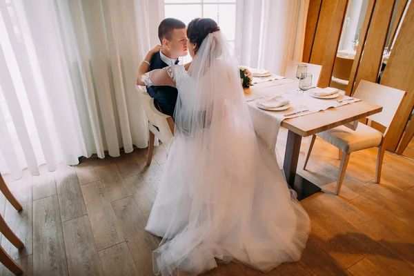 Feliz recién casados abrazando y hablando de su nueva vida matrimonial en el restaurante en la mesa —  Fotos de Stock