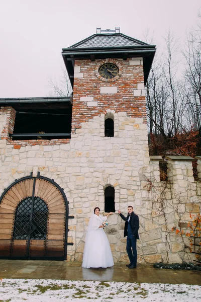Romantisches verliebtes Brautpaar posiert vor winterlichem Hintergrund in der Nähe alter Burgmauern — Stockfoto