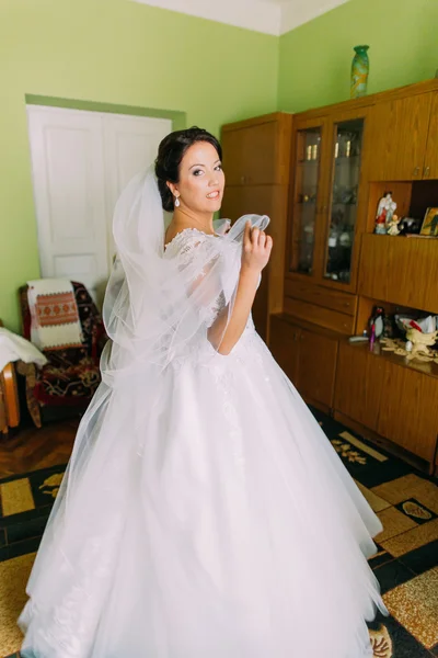 Hermosa novia en casa en vestido de novia blanco, concepto de los preparativos. Retrato de cuerpo entero — Foto de Stock