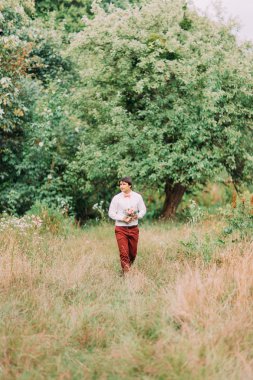 Onun için en iyi çiçekler. Yakışıklı genç adam giyen tam uzunlukta