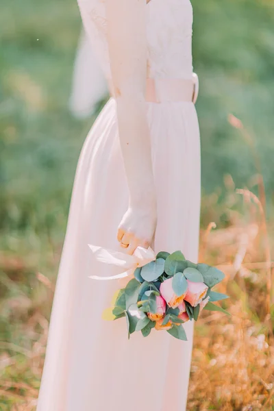 Bride wearing white dress at the summer forest with a wedding bouquet in hands, side view — Stock Photo, Image