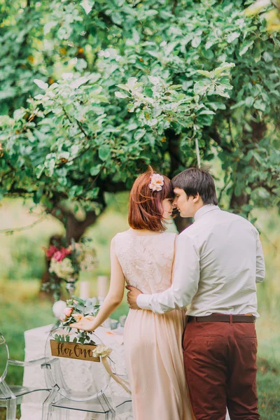 Braut und Bräutigam posieren am geschmückten Banketttisch im Sommerpark. Moment des Glücks genießen — Stockfoto