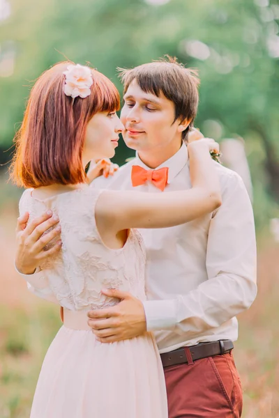 Mann hält Bräute zärtlich in der Taille vor dem Hintergrund des grünen Waldes, sie hält die Hand auf seinen Schultern — Stockfoto