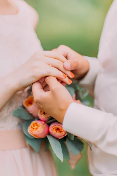Close-up mid section of a newlywed couple with wedding rings and bouquet — Stock Photo, Image
