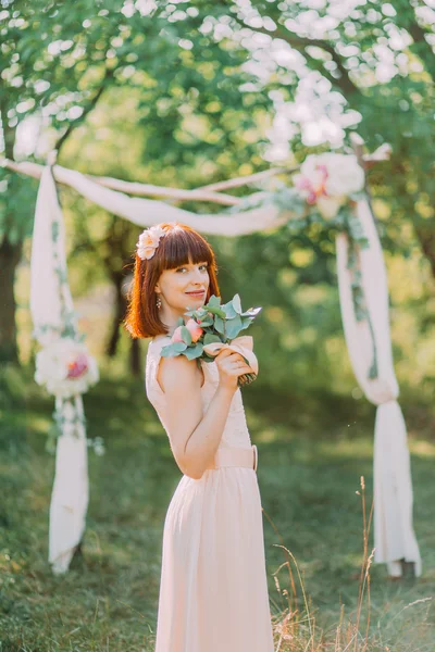 Bella sposa in abito da sposa e con bouquet da sposa in posa alla cerimonia all'aperto — Foto Stock