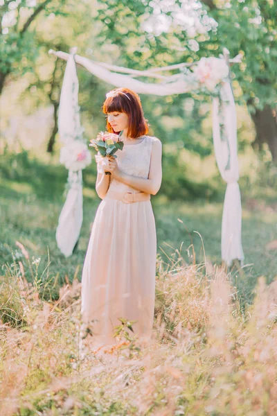 Volle Länge der Braut Blick auf Brautstrauß im Freien, Dekor Bogen als Hintergrund — Stockfoto