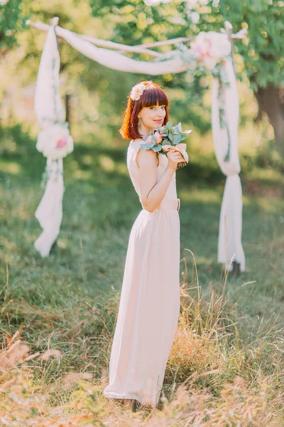 Schöne Braut im Wald, Hochzeitskleid Farbe der Ruhe. Bogen mit Blumen. — Stockfoto