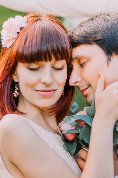 Närbild. Lycklig brud och brudgum på deras bröllop kramar i parken — Stockfoto
