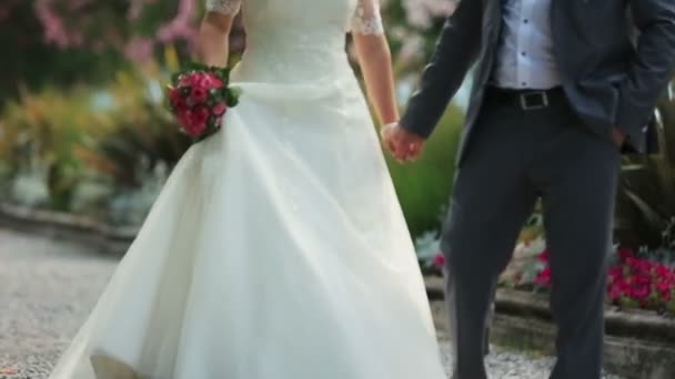 Mooie bruidspaar wandelingen en houdt handen close-up. Como, Italië — Stockvideo