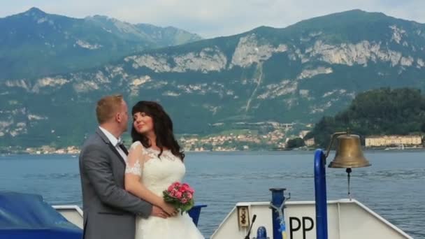 結婚式のカップルが、ヨットの上でキスします。イタリアのコモでの新婚旅行 — ストック動画