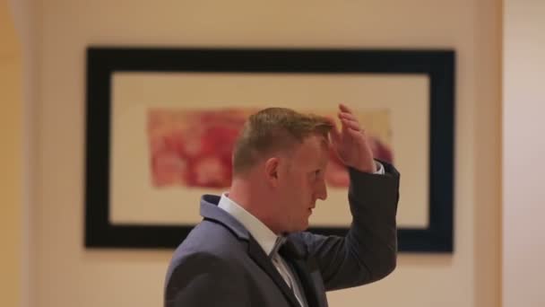 Portrait of young handsome man fixing his hairstyle in hotel room — Stock Video