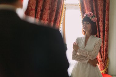 Pencere sevgiyle ayakta gülümseyen gelin damat kapalı portre görünüyor.