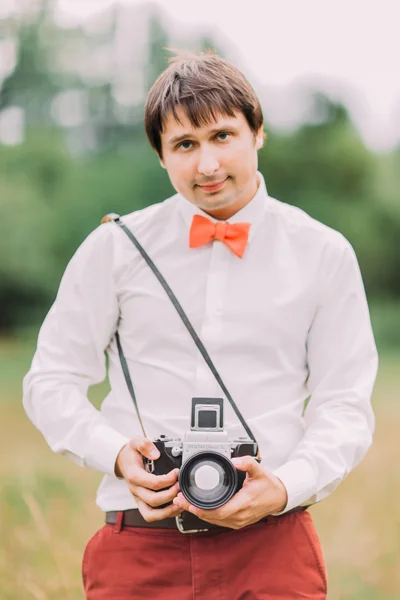 People, photography, technology, leisure and lifestyle - close up of young hipster man with retro vintage film camera on nature
