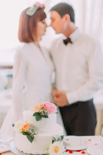Felice coppia si bacia sullo sfondo incredibile gustosa torta decorata fiori rosa — Foto Stock