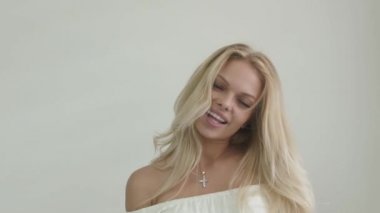 Beyaz üst pozlar ve gülümsüyor çekici bir sarışın kız Close-up stüdyo görüntüleri