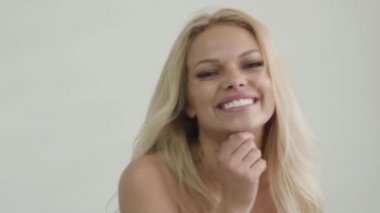 Çekici tabaklanmış sarışın kız yakın çekim stüdyo görüntüleri kameraya gülümsüyor