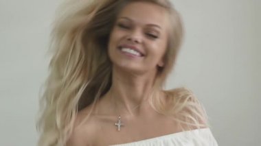 Beyaz üst çekici genç sarışın kız Close-up stüdyo görüntüleri gülüyor ve saçları ile çalış