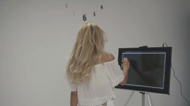 Beyaz üst çekici sarışın kız diş sağlığı şirketi için logo çizmek için çalışır