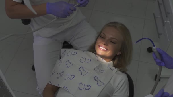 Patient in dentist cabitet. Beautiful girl with shining smile sitting in dentists chair — Stockvideo