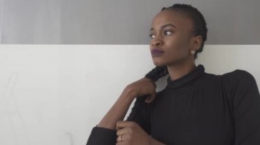 Karanlık stüdyo arka plan üzerinde bakarak onu kalın plait dokunarak güzel Amerikalı kadının yakın çekim