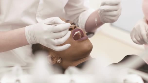 Joven afroamericano negro hembra apertura boca mientras dentista en blanco látex guantes y máscara, su asistente comprobar el estado de sus dientes — Vídeo de stock