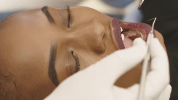 Vista lateral del dentista y la enfermera haciendo examen dental profesional paciente joven mujer en el consultorio dental — Vídeos de Stock