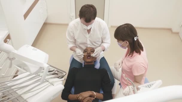 Dentiste masculin avec assistant examinant les dents des femmes dans la chaise des dentistes, gros plan, vue du dessus — Video