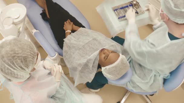 顶视图的牙医和护士制作专业牙齿清洁女性年轻的病人，在牙科诊所 — 图库视频影像