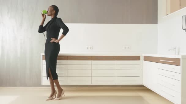 Side view of african-american businesswoman drinking coffee looking away at light office — Stock Video