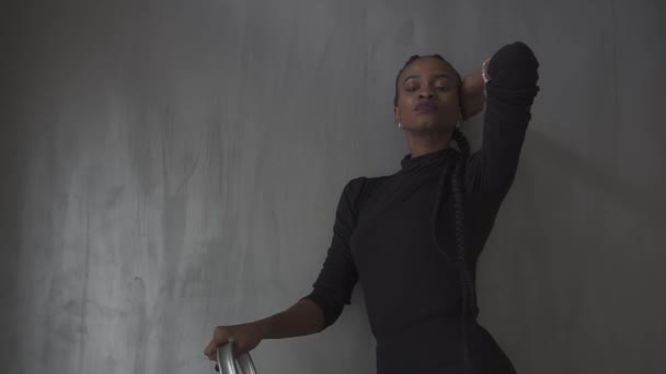 Confiant jeune femme noire en robe sombre posant en studio avec la main levée — Video