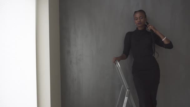 Pretty african american woman standing touching her thick plait on dark gray studio background — Stock Video