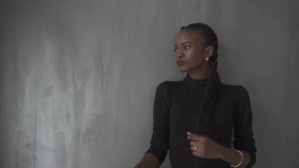 Retrato de cerca de la hermosa mujer joven en vestido negro con la mirada hacia otro lado, fondo gris — Vídeos de Stock