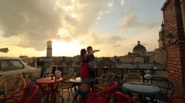 Usulca yağmur sırasında Antik şehir manzaralı çatı kafe öpüşme genç sevgi dolu çift. Arka planda bulutlar gökyüzünde ile romantik günbatımı