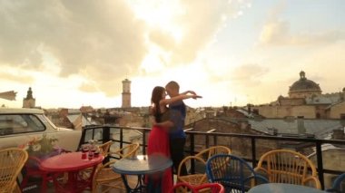 Usulca yağmur sırasında Antik şehir manzaralı çatı kafe öpüşme genç sevgi dolu çift. Arka planda bulutlar gökyüzünde ile romantik günbatımı