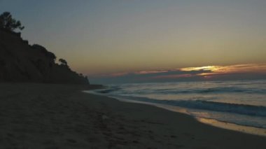Sessiz gün batımında kum sahilde yuvarlanan dalgaların timelapse. Deniz sakinliği kavramı